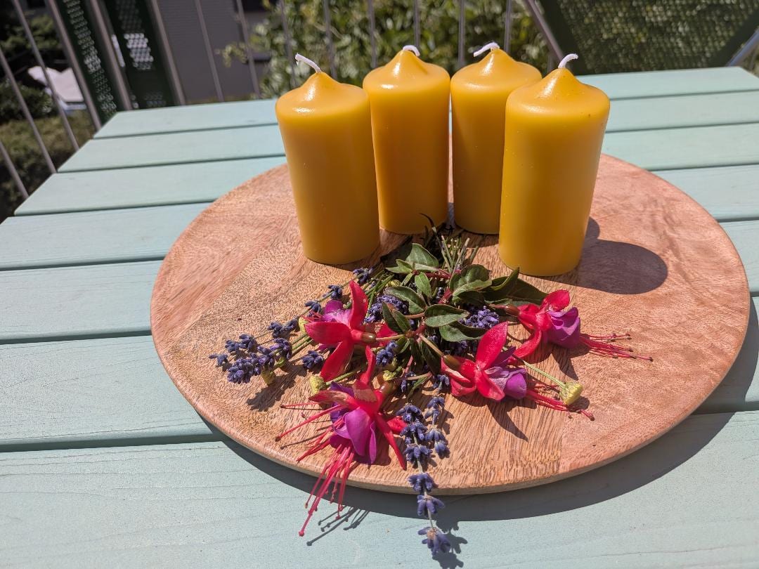 Vier kleine Bienenwachsstumpen in Adventsgröße auf Holzscheibe mit Lavendel