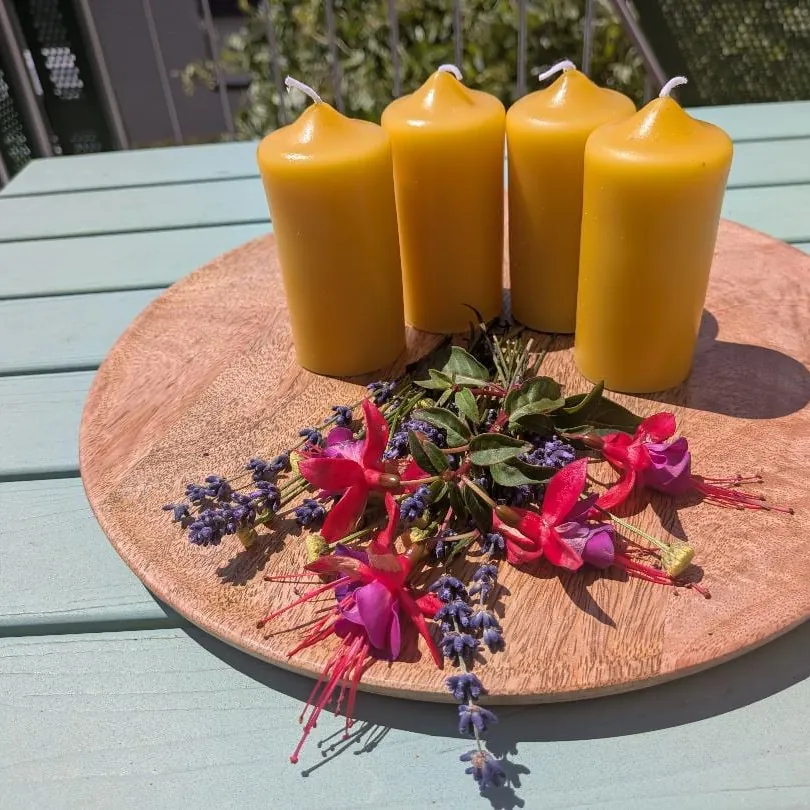 Vier kleine Bienenwachsstumpen in Adventsgröße auf Holzscheibe mit Fuchsien und Lavendel