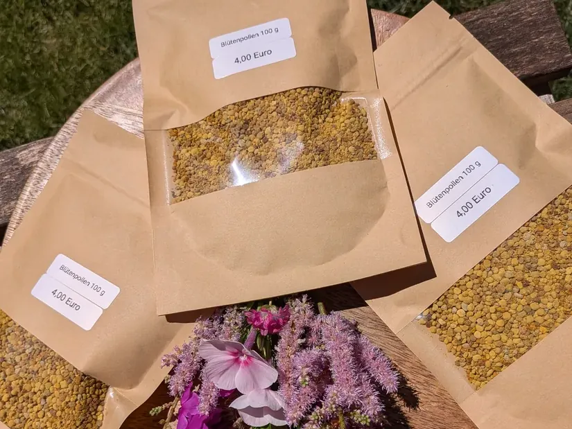 Drei Tüten Blütenpollen mit Sichtfenster auf einem Holztisch im Garten